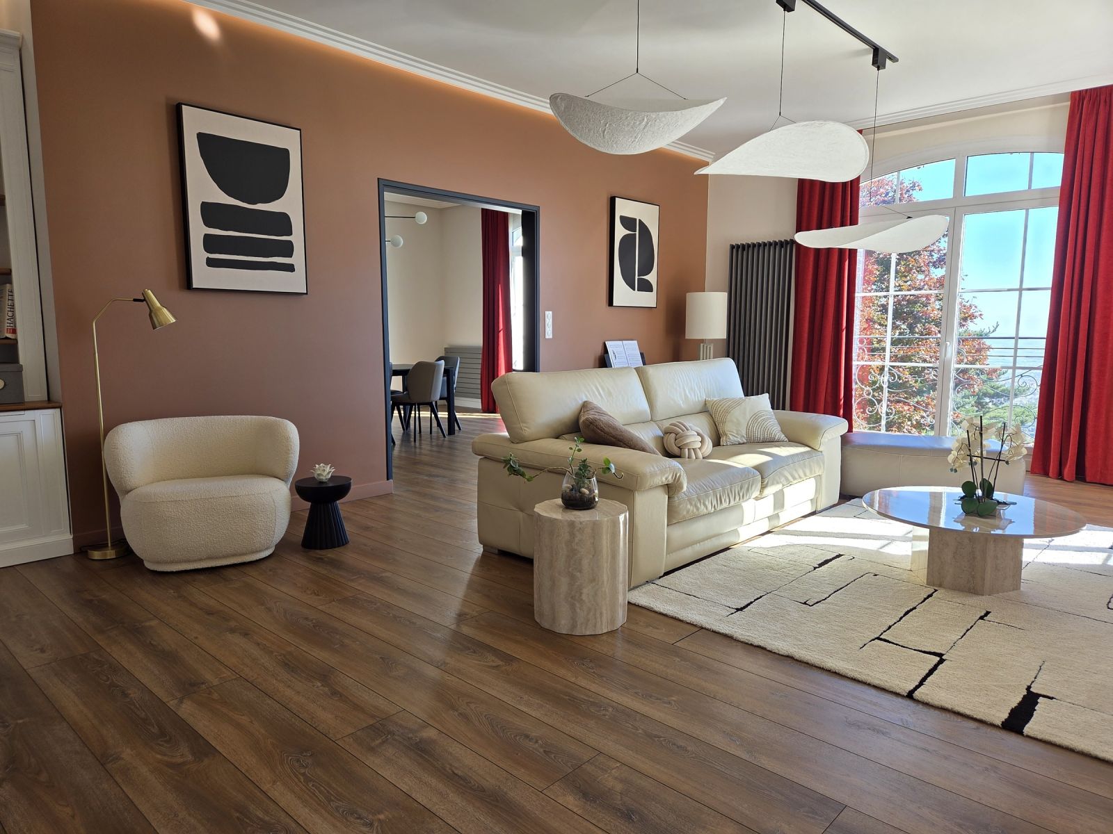 Séjour au mur terracotta, corniche à éclairage indirect et grandes fenêtres